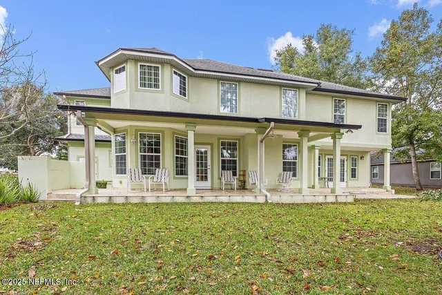 a view of a house with a big yard and large trees