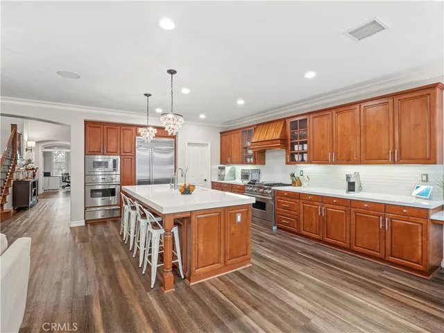 a kitchen that has a lot of cabinets stainless steel appliances and wooden floor