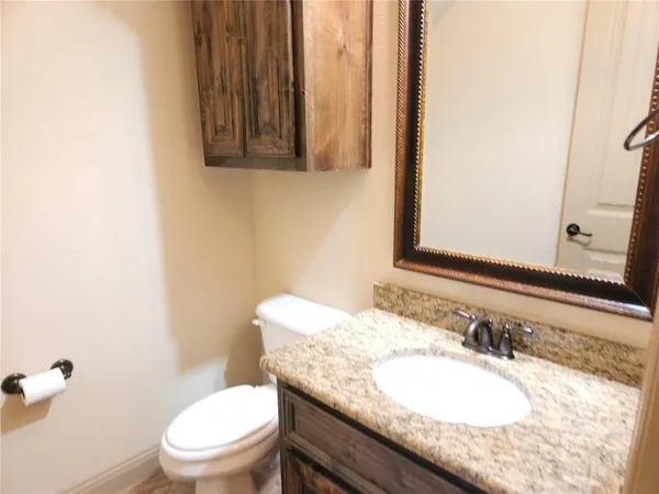 a bathroom with a granite countertop sink a mirror and a toilet