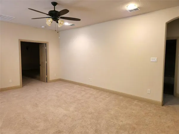 an empty room with a chandelier fan and a ceiling fan