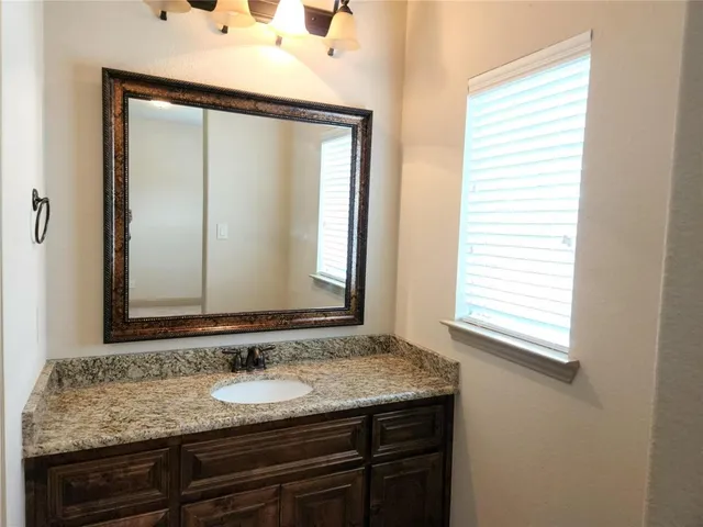 a bathroom with a granite countertop sink and a mirror