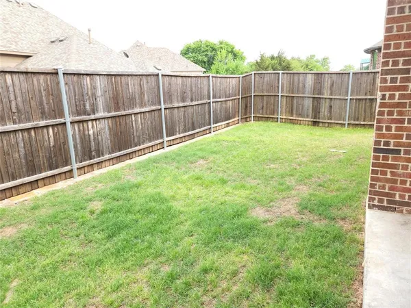a view of a backyard with a fence and wooden fence