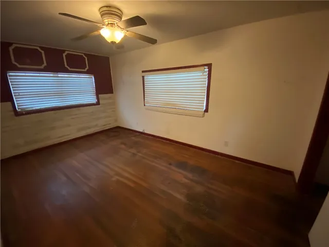 a view of an empty room with window and chandelier fan