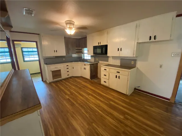 a large kitchen with a stove a sink dishwasher and a refrigerator with wooden floor