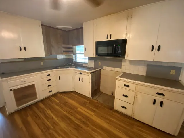 a kitchen with granite countertop a sink cabinets and stainless steel appliances