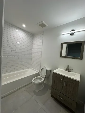 a bathroom with a bathtub shower sink vanity and toilet