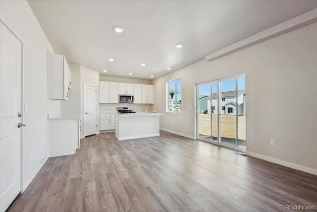 a view of an empty room with wooden floor and windows