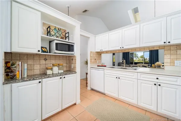 a kitchen with granite countertop white cabinets and stainless steel appliances