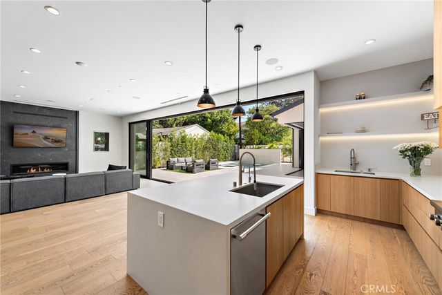 a kitchen with stainless steel appliances granite countertop a sink a stove and a wooden floors