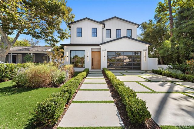 a front view of a house with a yard and potted plants