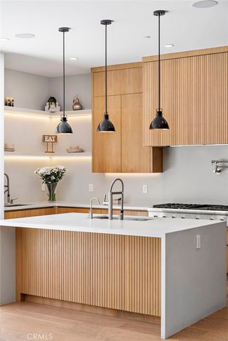 a kitchen with stainless steel appliances granite countertop cabinets a sink a center island and a wooden floor