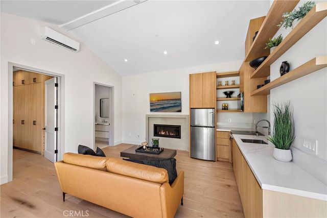 a living room with stainless steel appliances furniture a rug and a view of kitchen
