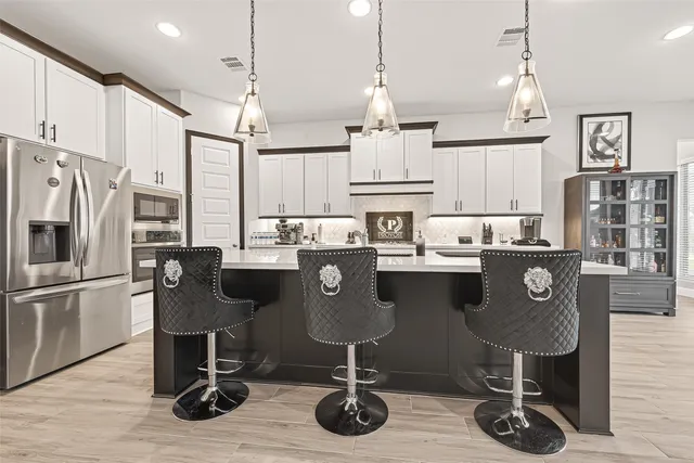a kitchen with stainless steel appliances granite countertop a refrigerator a stove and white cabinets