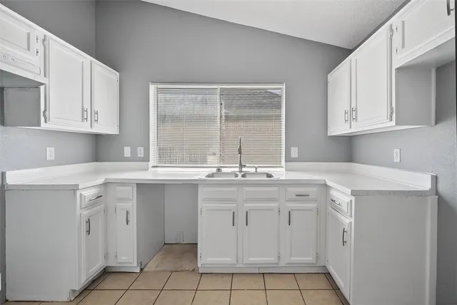a kitchen with white cabinets appliances a sink and a window