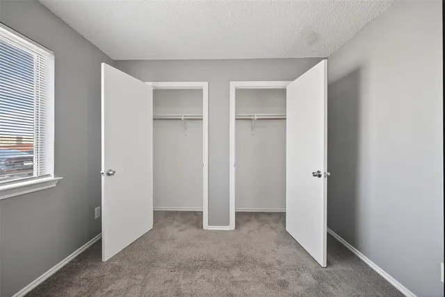a view of an empty room with closet and a window