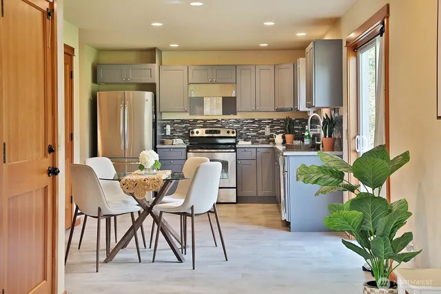 a kitchen with stainless steel appliances kitchen island granite countertop a refrigerator a stove a sink dishwasher and a dining table with wooden floor