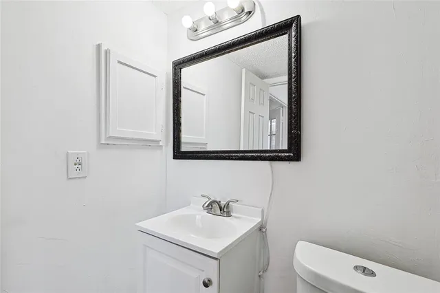 a bathroom with a toilet sink vanity and mirror