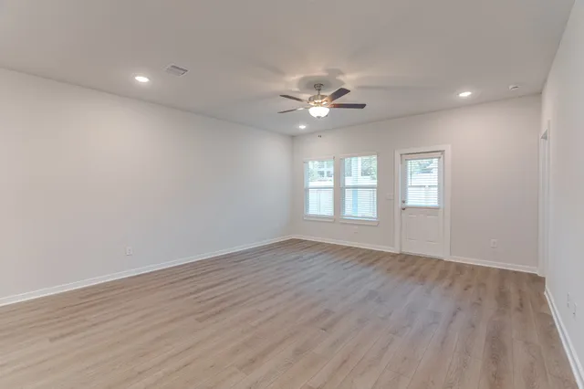 a view of an empty room with a window and wooden floor