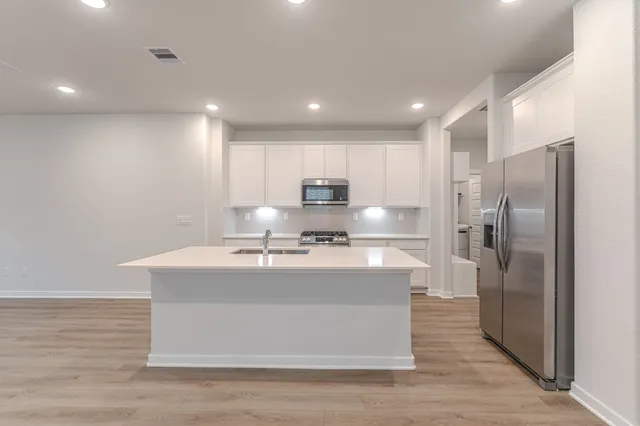 a kitchen with kitchen island a counter top space a sink stainless steel appliances and cabinets