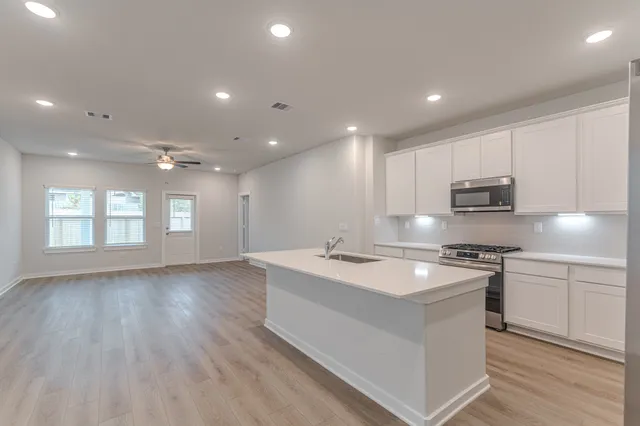 a kitchen with stainless steel appliances granite countertop a sink dishwasher a stove and a refrigerator with wooden floor