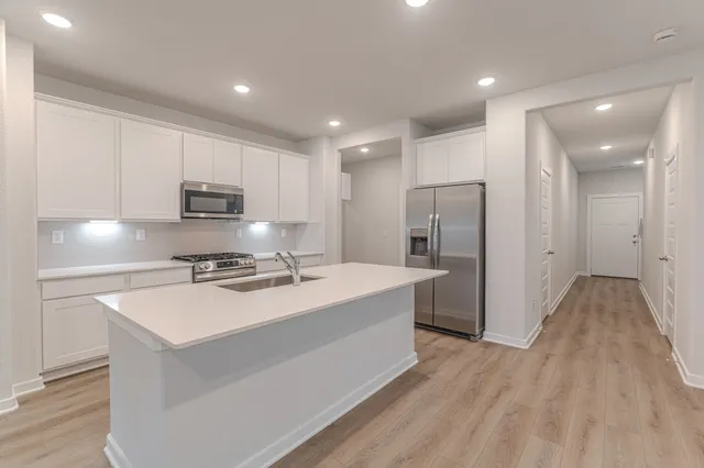 a kitchen with kitchen island a sink appliances and cabinets