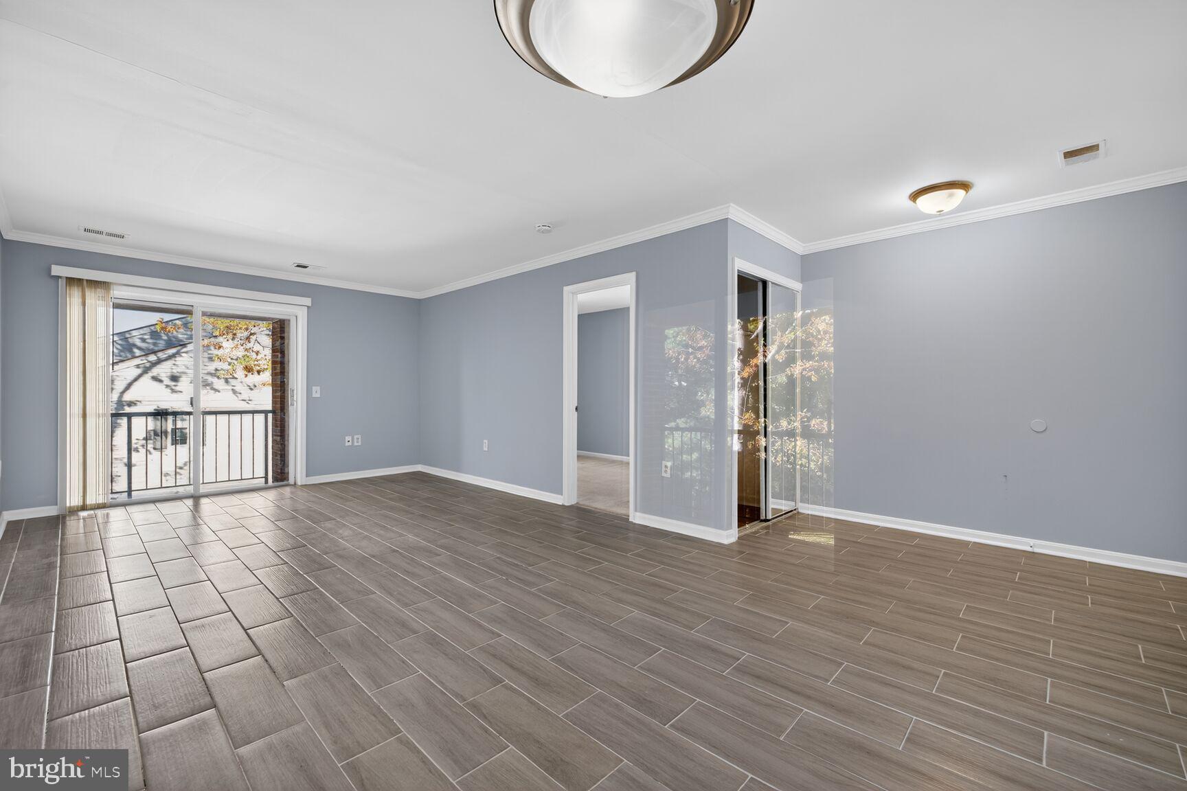18318 Streamside Drive, Unit 302 Gaithersburg, MD 20879 - Photo 4 of 17 a view of an empty room with wooden floor and a window