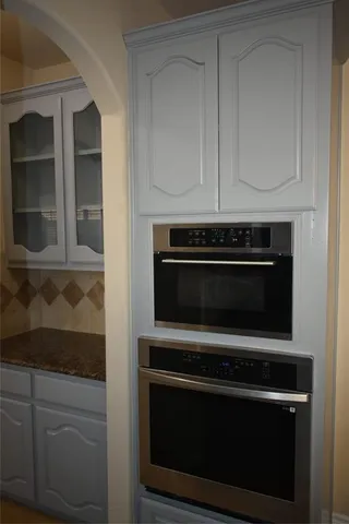 a kitchen with stainless steel appliances granite countertop a refrigerator a sink dishwasher a stove and a dining table with wooden floor