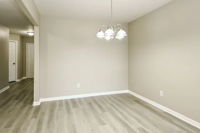 a view of empty room with wooden floor and chandelier