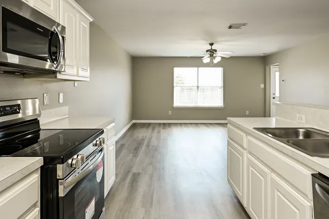 a kitchen with stainless steel appliances granite countertop a stove a sink and a microwave