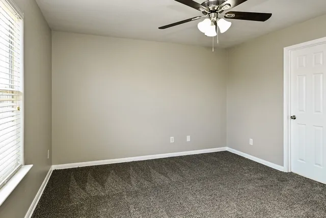 an empty room with a window and a fan