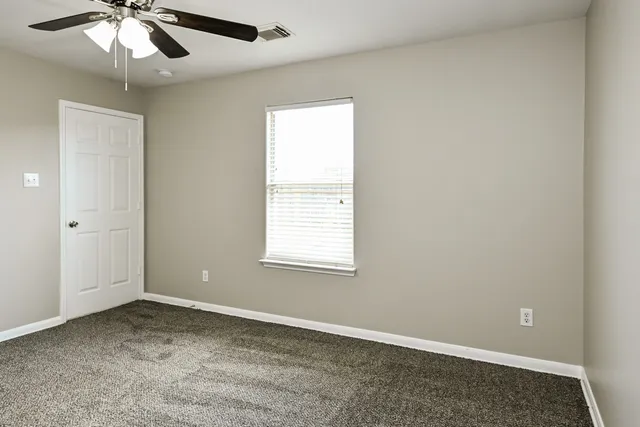 an empty room with a window and a ceiling fan