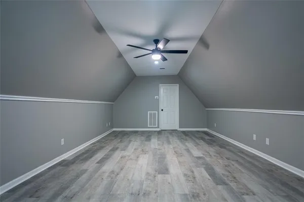 an empty room with wooden floor and fan