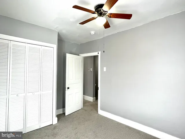 a view of an empty room with window and a ceiling fan