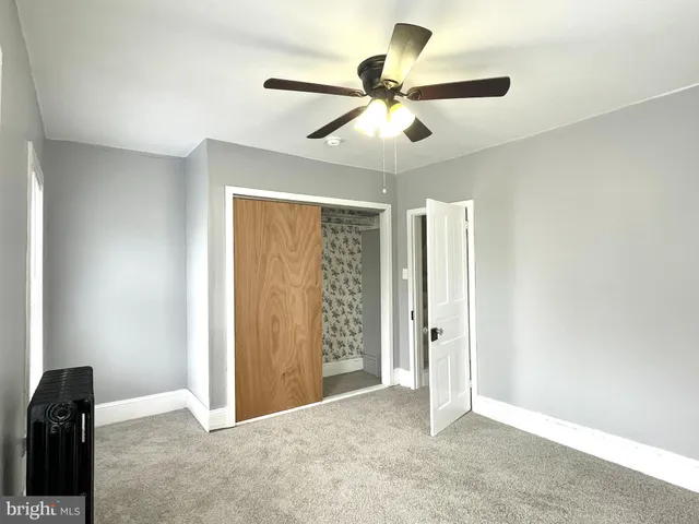 an empty room with closet and a ceiling fan
