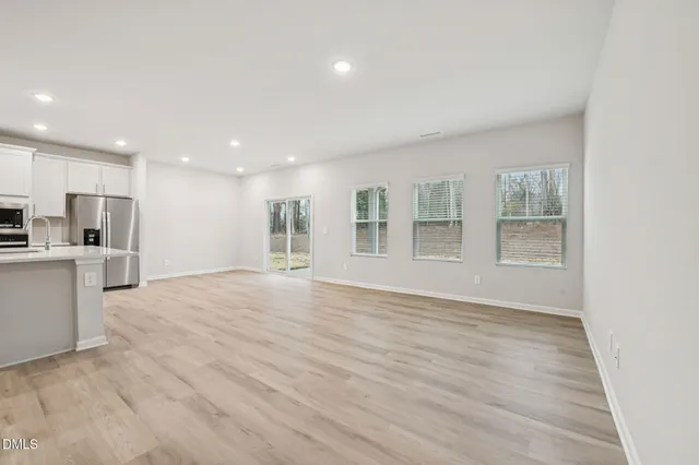 a large kitchen with stainless steel appliances granite countertop a stove a refrigerator a oven and a cabinets with wooden floor