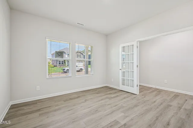 an empty room with wooden floor and windows
