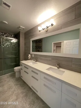 a bathroom with a double vanity sink toilet mirror and shower