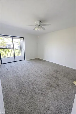 an empty room with windows and ceiling fan