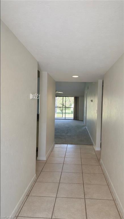 1228 Commonwealth Circle, Unit O203 Naples, FL 34116 - Photo 2 of 17 a view of hallway with a window and a refrigerator