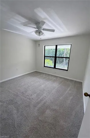 an empty room with windows and ceiling fan