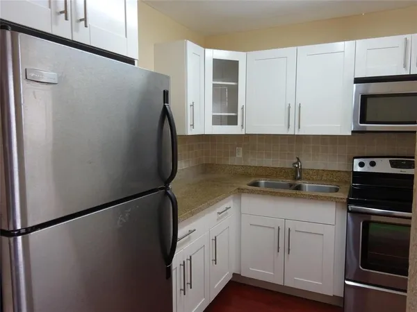 a kitchen with stainless steel appliances white cabinets and a refrigerator