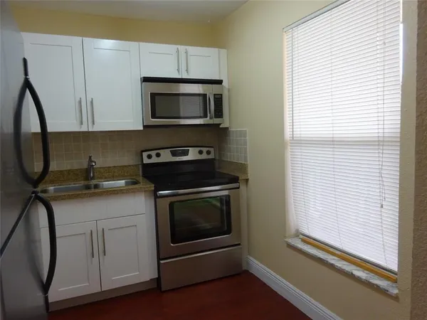 a kitchen with white cabinets and black appliances