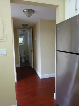 a view of a hallway with wooden floor and a bathroom