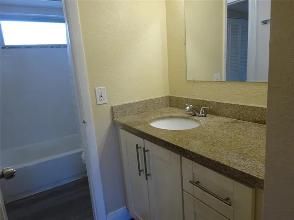 a bathroom with a granite countertop sink and a mirror