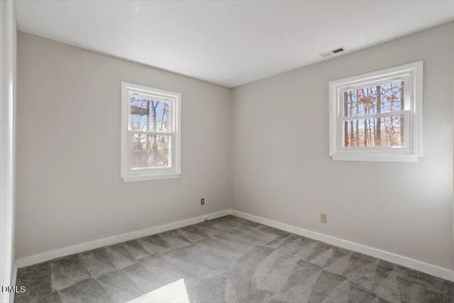 a view of an empty room with windows and closet