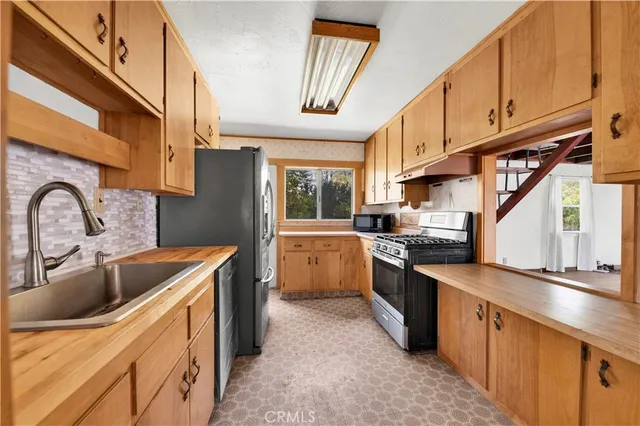 a kitchen with granite countertop a sink a counter top space stainless steel appliances and cabinets