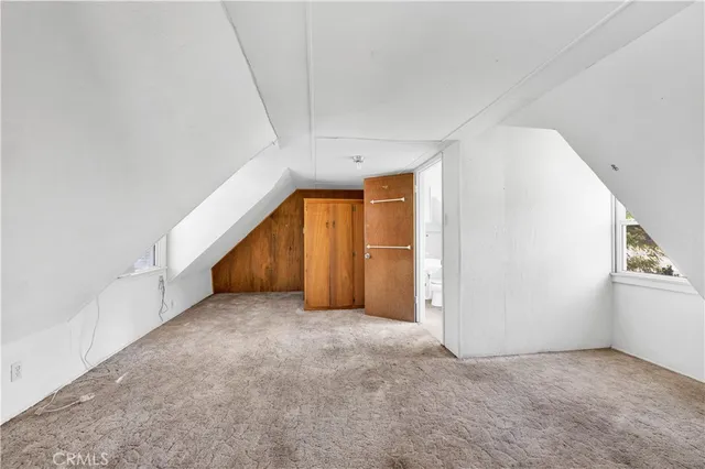 a view of an empty room with wooden floor and stairs