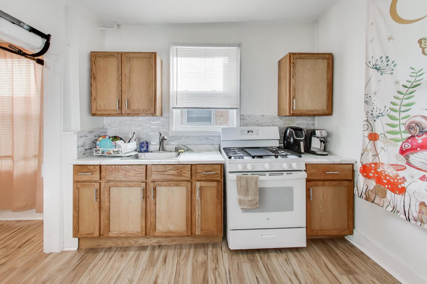 3248 South Paulina Street Chicago, IL 60608 - Photo 7 of 43 a kitchen with stainless steel appliances white cabinets and wooden floor