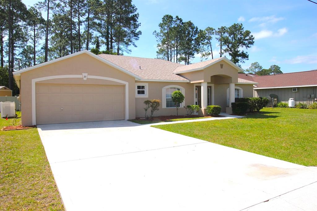 32 Ryding Lane Palm Coast, FL 32164 - Photo 1 of 38 a front view of a house with a yard and trees