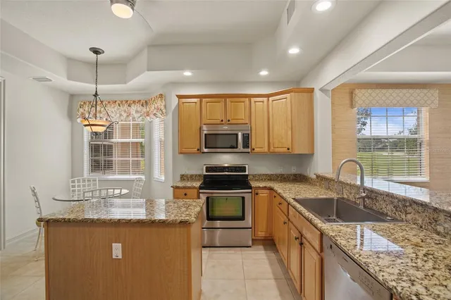 a kitchen with stainless steel appliances granite countertop a sink stove refrigerator and cabinets